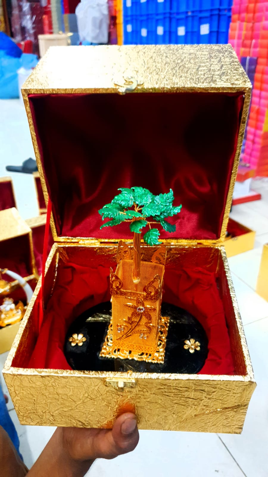 Decorative golden Tulsi plant showpiece with green leaves in a premium red-lined gift box