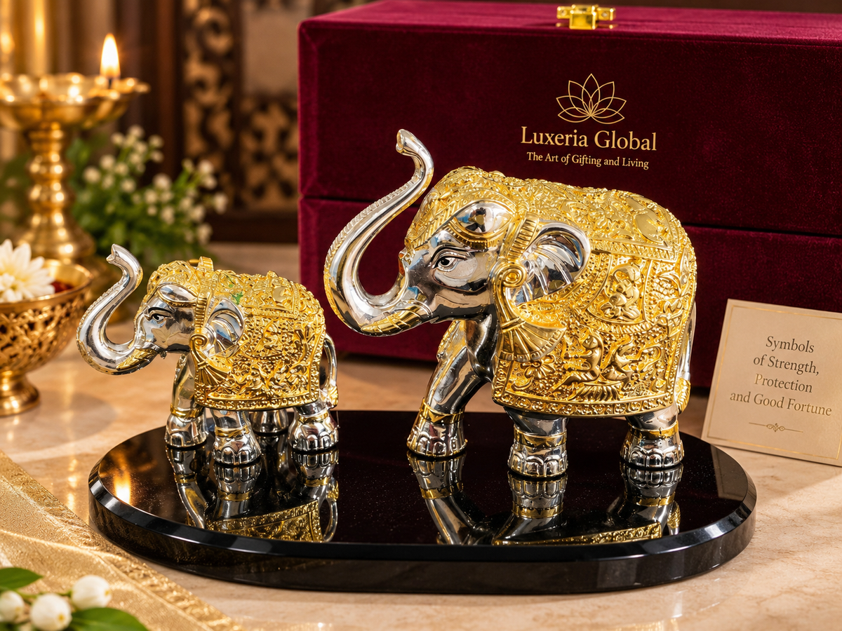 Gold and silver-polish mother and baby elephant décor with raised trunks on a black oval base